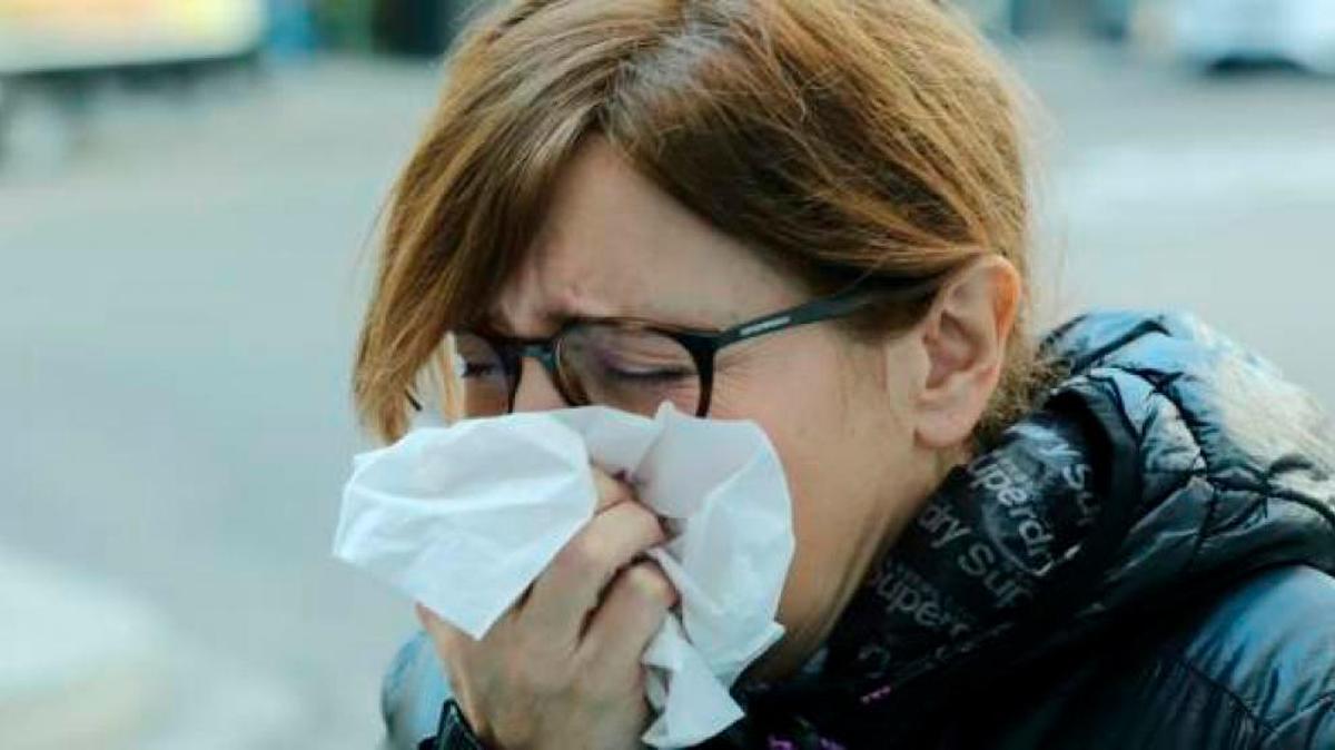 Una mujer se protege con un pañuelo mientras tose.