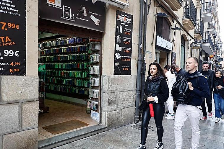 Una joven pasea junto a un establecimiento sin puerta, solo con trapa.