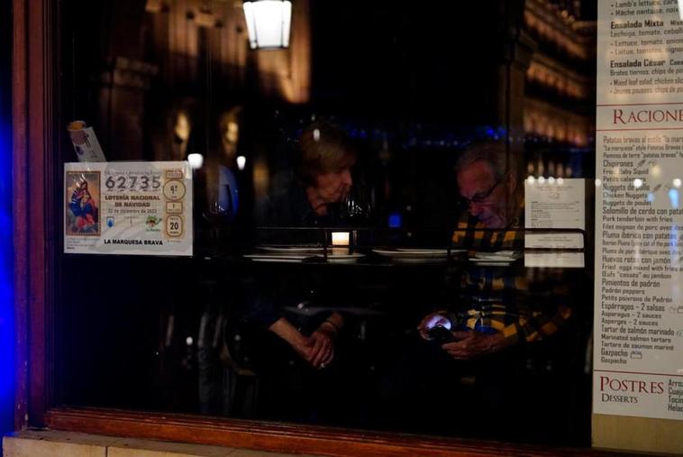 Dos clientes permanecen en el interior de un bar durante el apagado de luces.