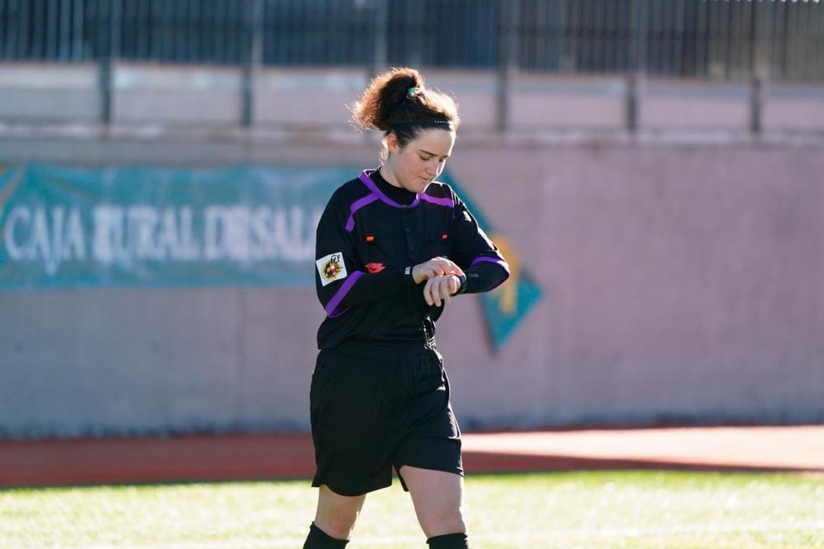 Una árbitro mira el reloj durante un partido del fútbol base