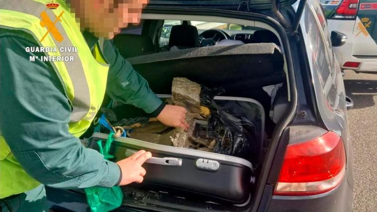 Un guardia civil saca los fardos de hachís del maletero del vehículo.