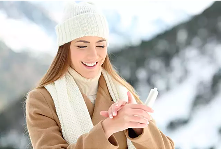 Una mujer se da crema hidratante en las manos