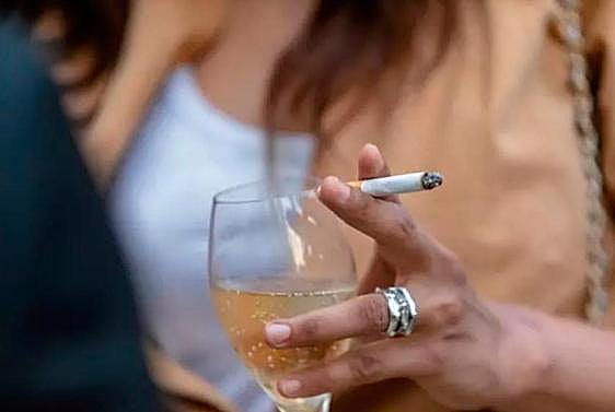 Una mujer bebiendo y fumando