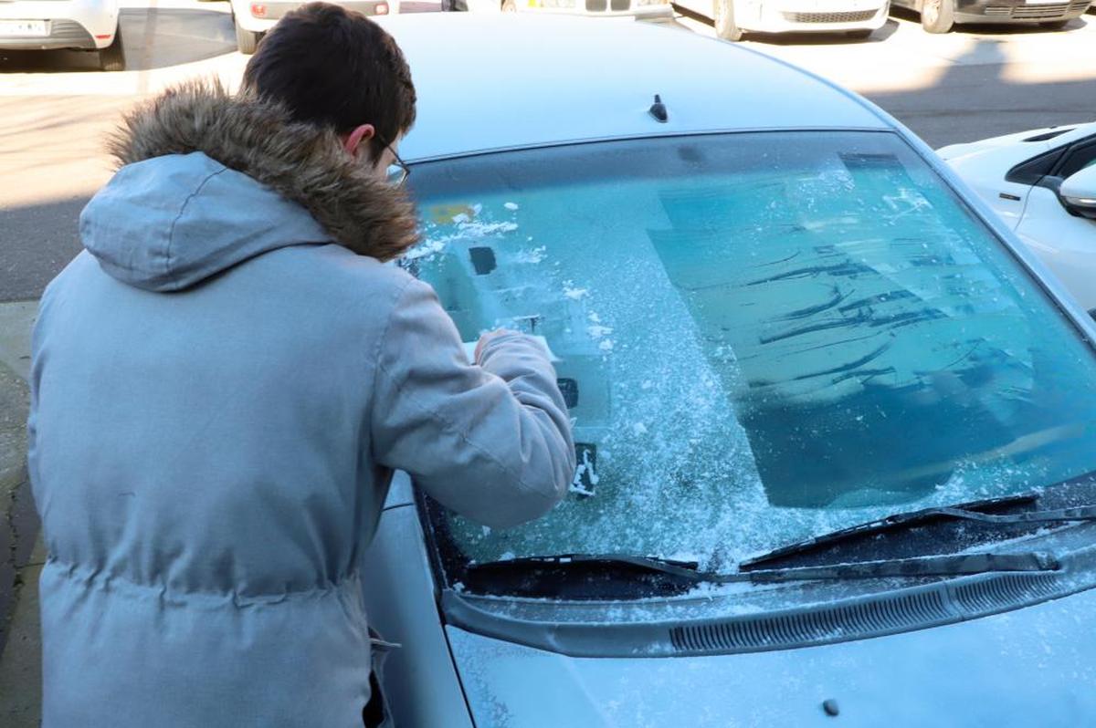 Una salmantina retirando la escarcha de su coche. SERNA