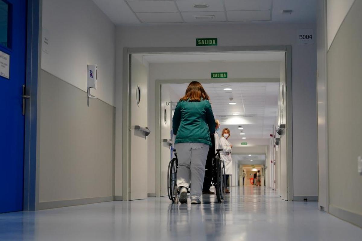 Un profesional del Hospital tras a un paciente en silla de ruedas