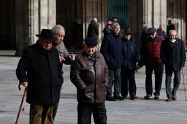 Varios grupos de personas mayores paseando por la Plaza Mayor.