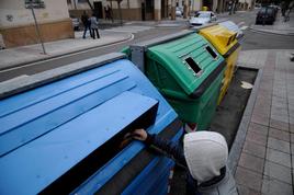 Un joven arroja papeles en un contenedor de reciclaje