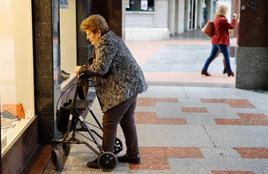 Una mujer pensionista mira una tienda de zapatos.