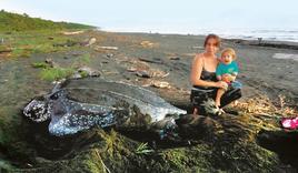 Bárbara Barrera, junto a uno de sus hijos custodiando una tortuga marina en el refugio de vida silvestre Laguna Urpiano.