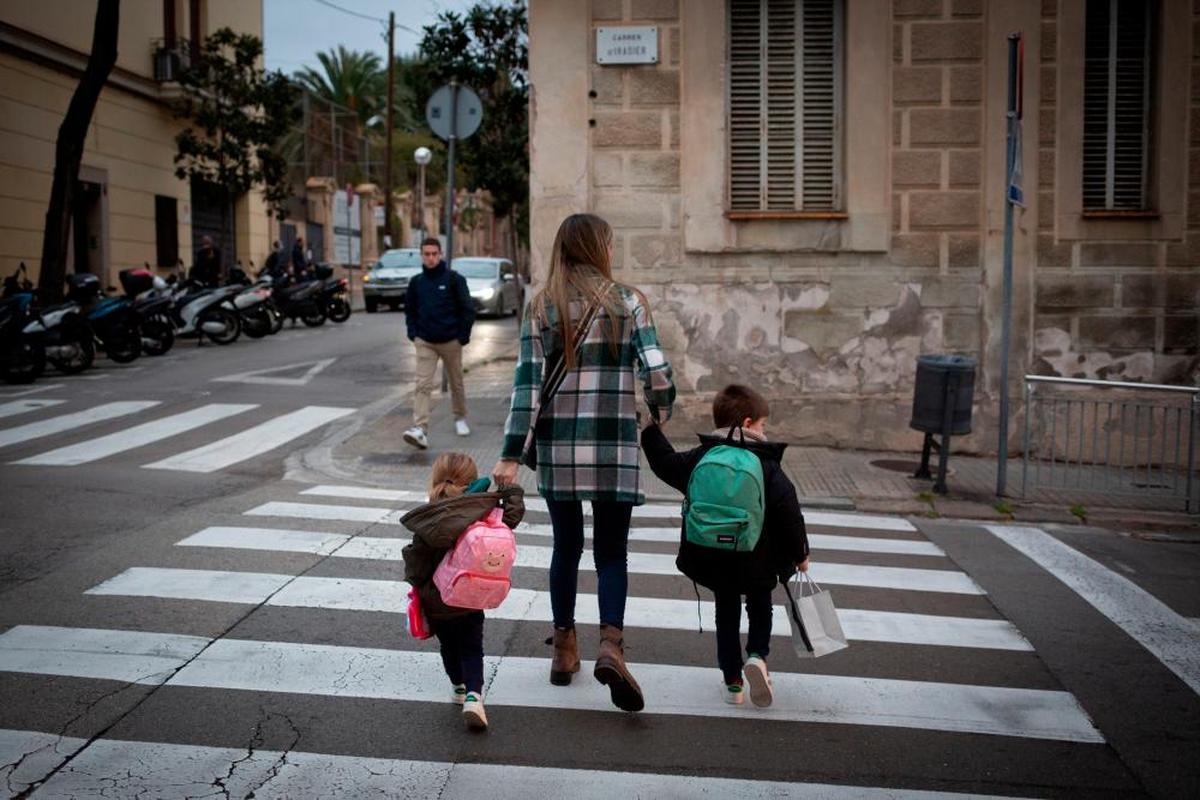 Una madre lleva a sus dos hijos al colegio.
