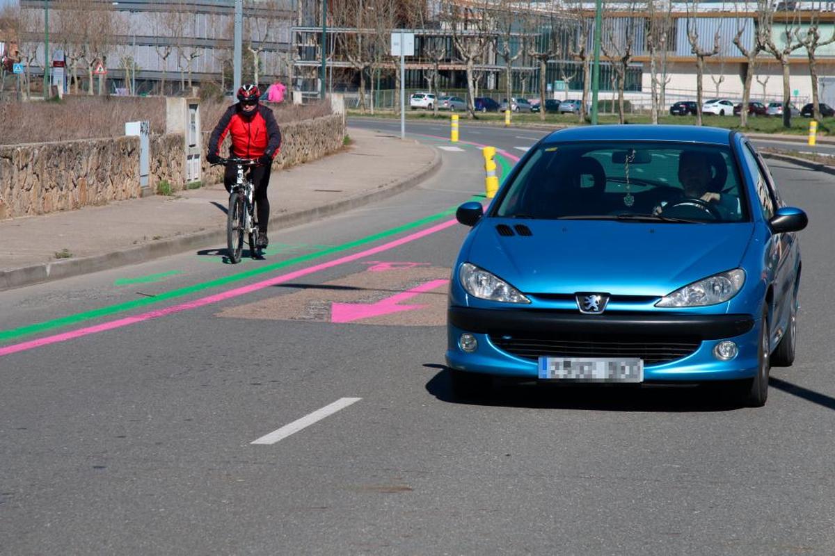 Un ciclista recorre la nueva organización de carril bici y peatonal en la zona de Gudino mientras un coche circula.