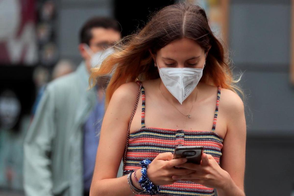 Una mujer camina por la calle con una mascarilla FPP2.