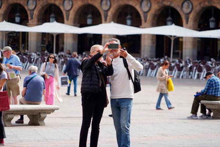 Una pareja de turistas en la Plaza Mayor disfruta del buen tiempo
