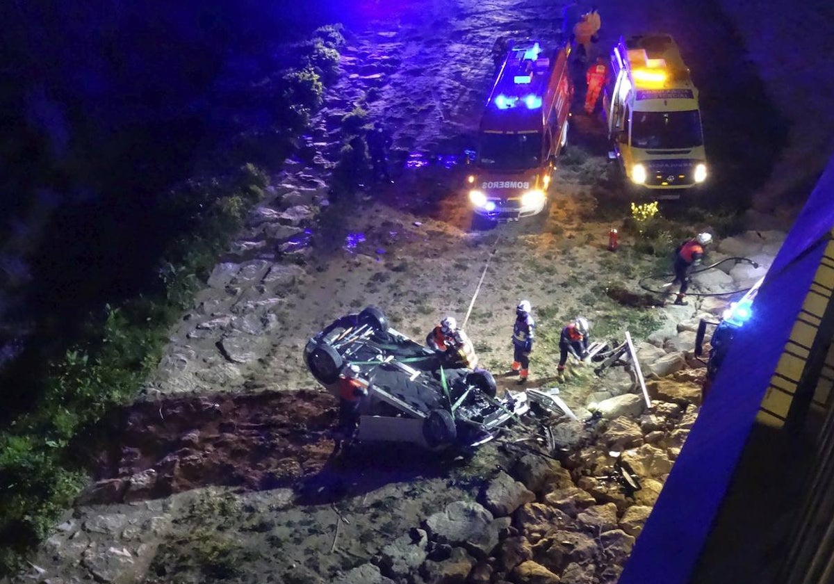 Los bomberos retiran el vehículo tras precipitarse.