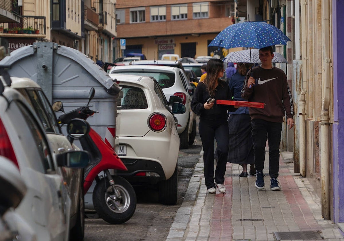 Una pareja camina bajo un paraguas por la calle Melchor Cano.