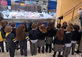 Un grupo de escolares escucha las indicaciones en la pescadería de Gadis