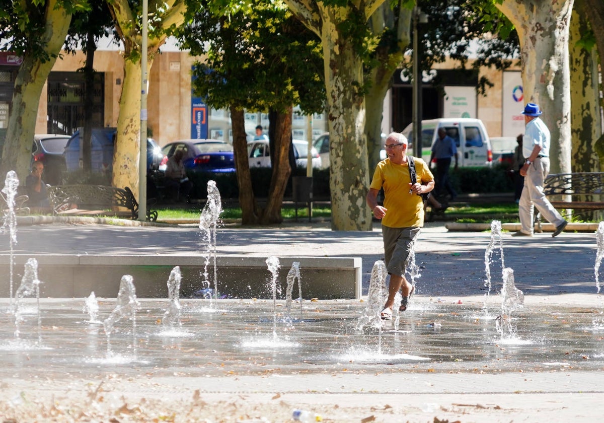 Un salmantino, paseando por el medio de una de las fuentes de la ciudad para refrescarse ante el calor