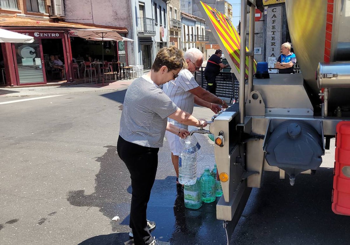 Dos vecinos de Vitigudino rellenan garrafas de agua potable en la céntrica Cuatro Calles