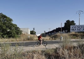 Un ciclista cruza la antigua vía del trazado Plasencia-Astorga, cubierta de maleza.