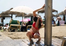 Mujer quitándose la arena en las duchas de la playa.