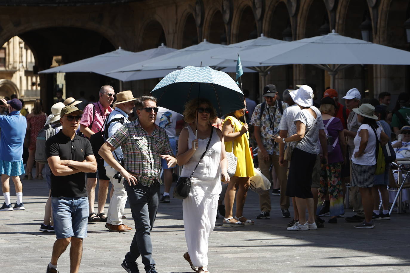 Varios turistas se refugian bajo los paraguas durante la tarde de este martes en Salamanca.