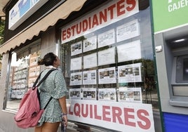 Una joven mira las ofertas de pisos de alquiler para estudiantes en una inmobiliaria.