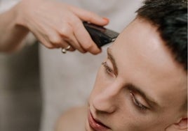 Imagen de un joven cortándose el pelo con maquinilla eléctrica.