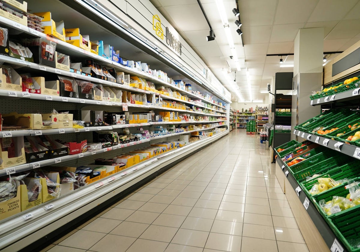 Pasillo de un supermercado con productos lácteos y verduras.