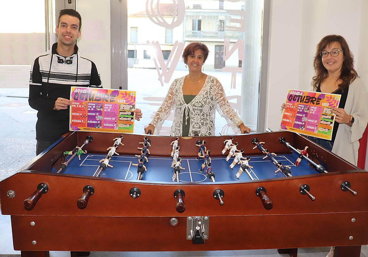Iván Hernández, Ana Aveleira y Sara García junto al futbolín que acogerá el viernes un campeonato.