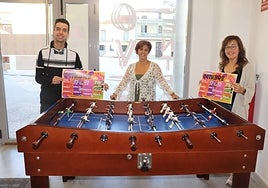 Iván Hernández, Ana Aveleira y Sara García junto al futbolín que acogerá el viernes un campeonato.
