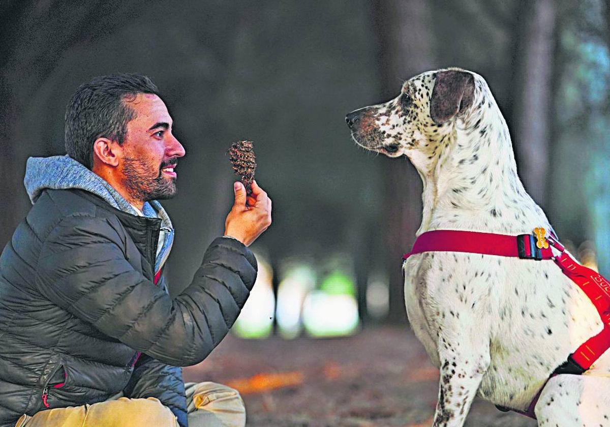 Un salmantino, en una zona verde de la ciudad junto a su perro.