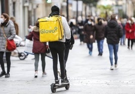 Un repartidor circula en patinete por una calle céntrica de la ciudad.