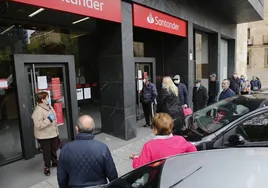 Varias personas esperando en un banco para cobrar la pensión.