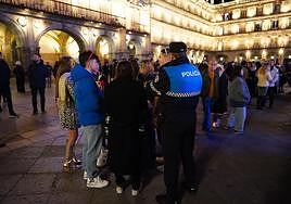 Un policía local conversa con un grupo de personas en la Plaza Mayor poco antes de las Campanadas.