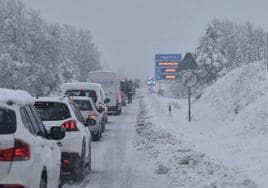 Una fila de coches parados en una carretera nevada