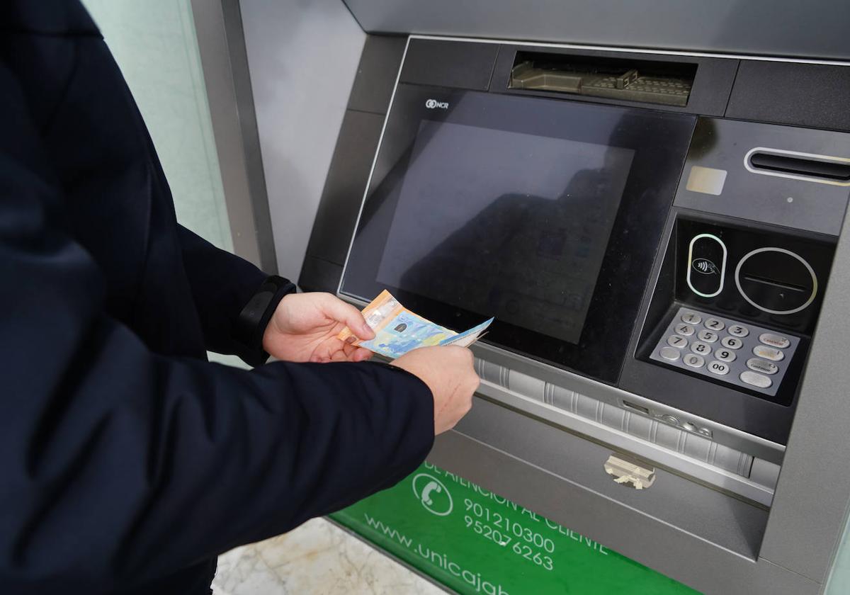 Un joven saca dinero de su cuenta corriente en un cajero automático de Salamanca.
