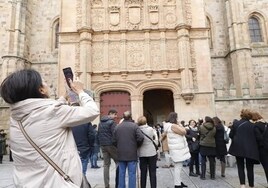 Turistas, abrigados, frente a la fachada de la Universidad.