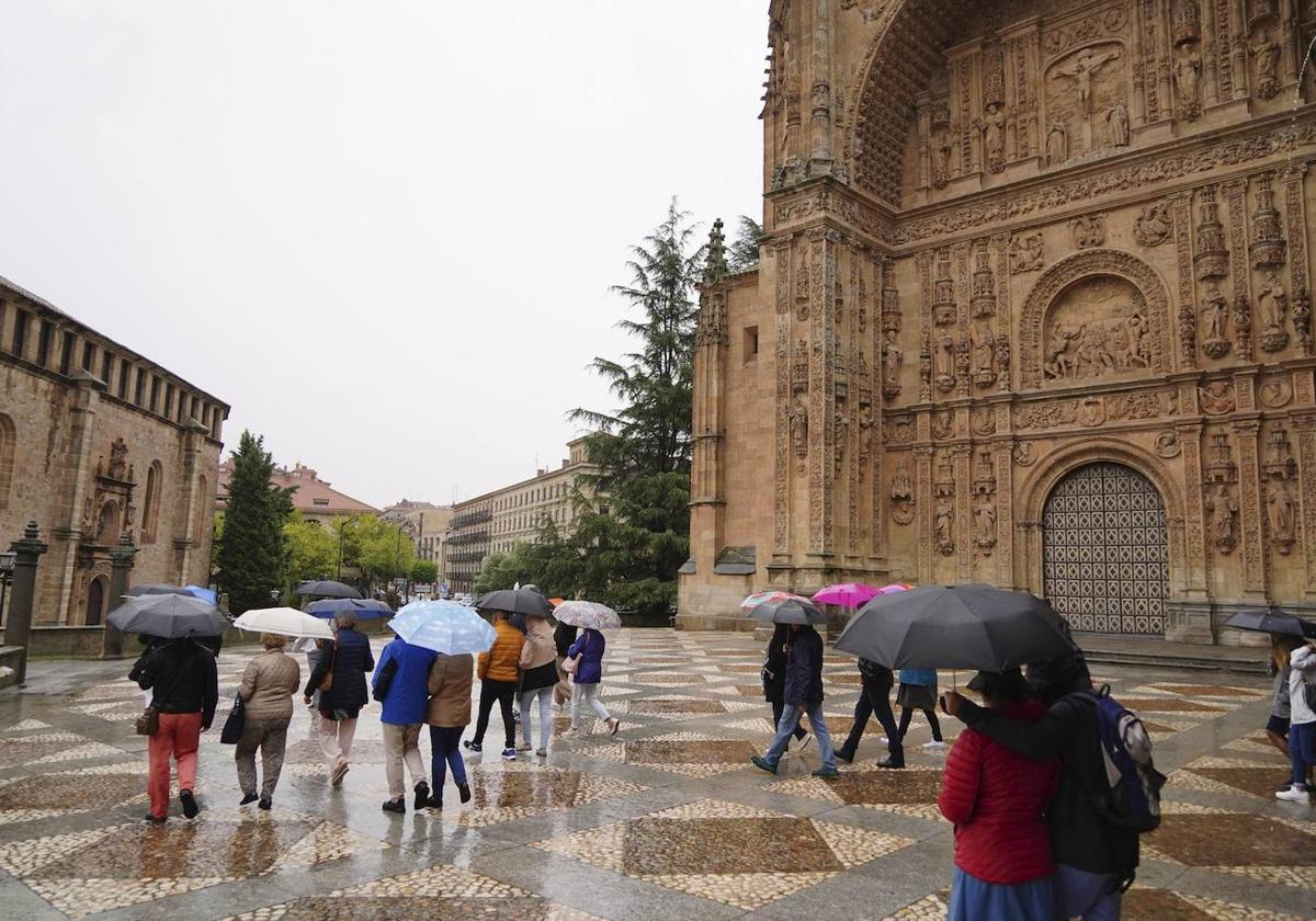 Gente resguardándose de la lluvia con paraguas en la plaza del Concilio de Trento