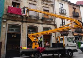 Operarios colocan un respostero en un balcón de la Rúa