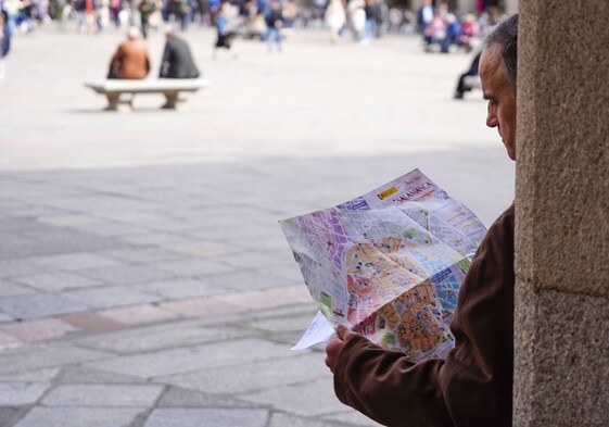 Un turista consulta un plazo de la ciudad en la Plaza Mayor.