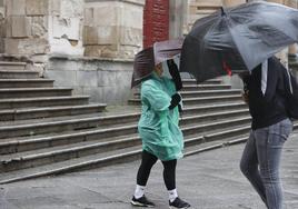 Viandantes se enfrentan a la lluvia y el viento en la calle Compañía