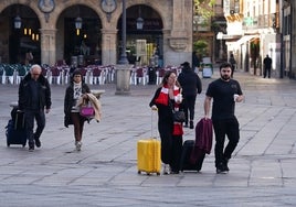 Turistas cruzan la Plaza Mayor con sus maletas.