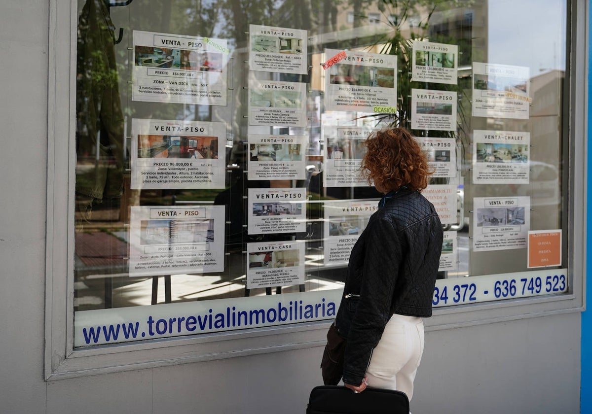 Una mujer observa las ofertas de viviendas en una inmobiliaria.