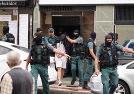 Los agentes salen con uno de los detenidos del local inspeccionado en la carretera de Ledesma durante el operativo.