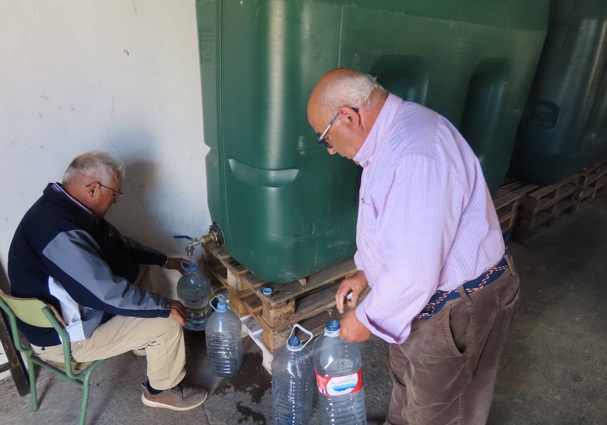 Dos vecinos llenan garrafas de agua para el consumo en su hogar.