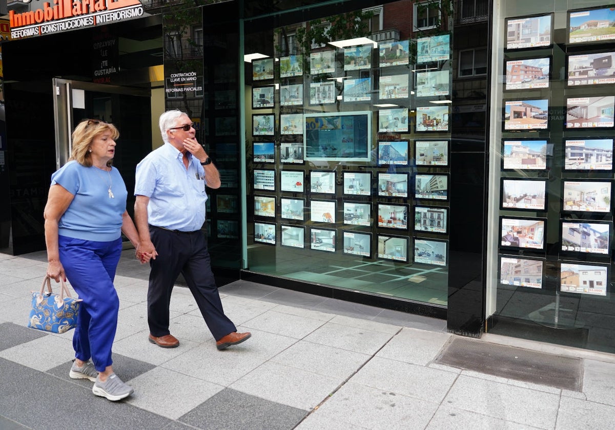 Una pareja pasa ante el escaparate de una inmobiliaria