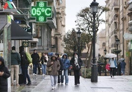 Salmantinos y turistas pasean por una de las calles más céntricas de la ciudad con chubasqueros y paraguas.