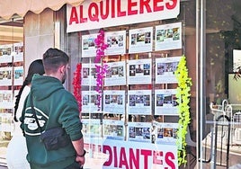 Dos jóvenes observan los anuncios de pisos de estudiantes en una inmobiliaria de Salamanca.