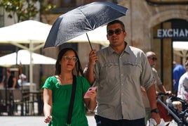 Una pareja se protege del sol con un paraguas mientras pasea por el centro de Salamanca.