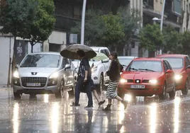 Varias personas pasean bajo la lluvia de Salamanca.